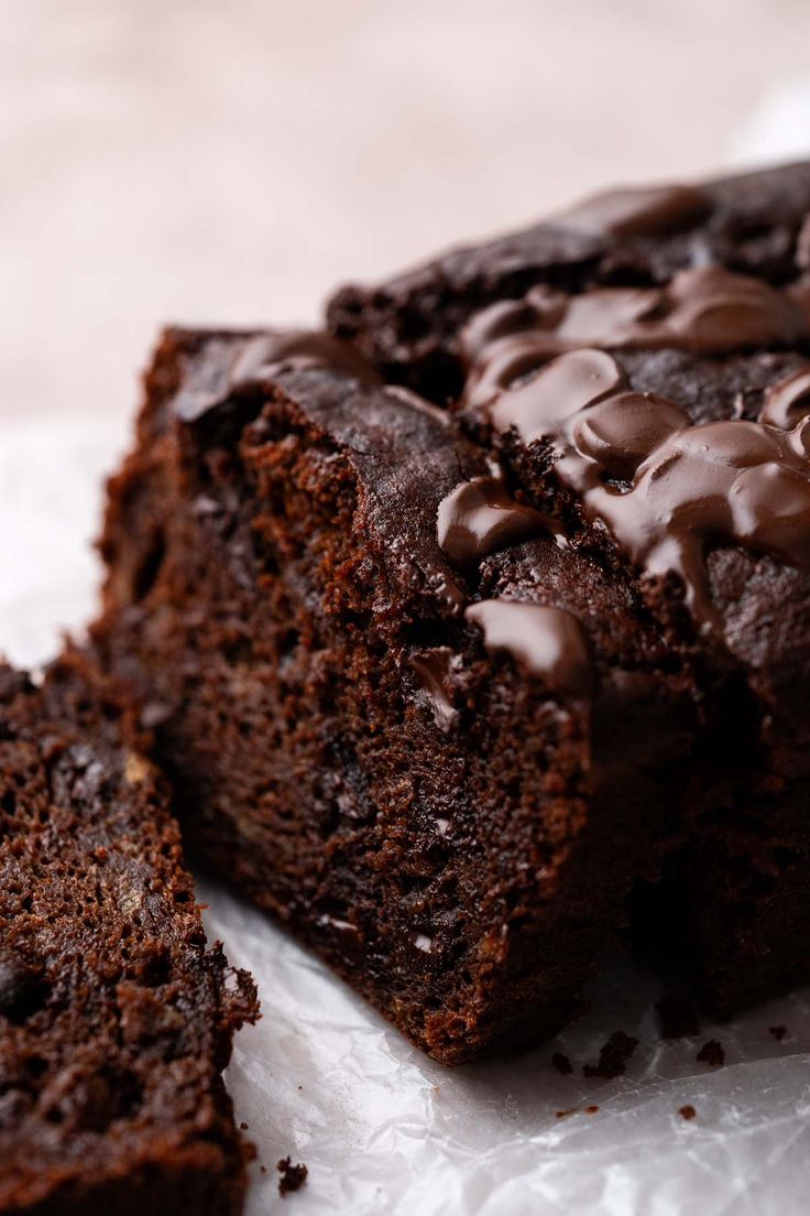 two pieces of chocolate cake sitting on top of white paper