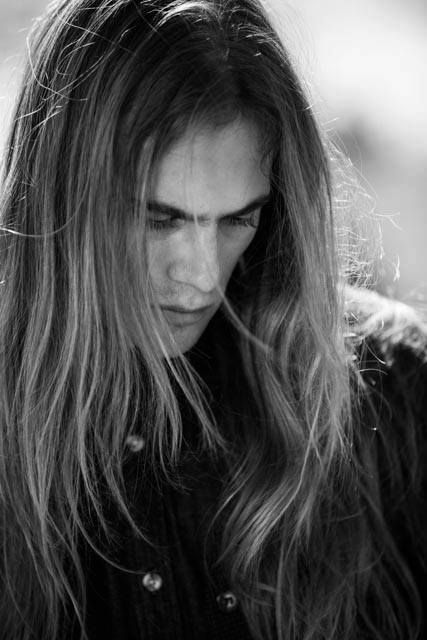 a man with long hair looking down at his cell phone