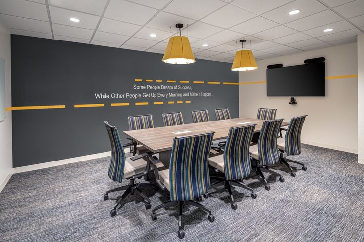 an empty conference room with chairs and a projector screen on the wall in front of it