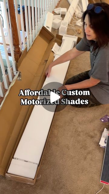 a woman sitting on the floor next to a cardboard box