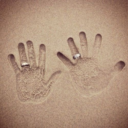 two hand prints in the sand with rings on them