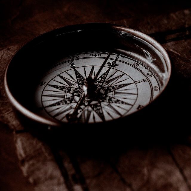 a close up of a compass on a piece of wood with an arrow in the middle