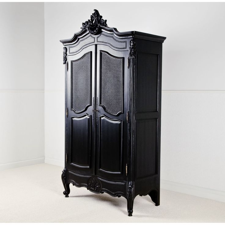 an ornate black armoire stands against a white wall