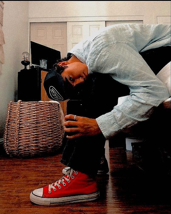 a man is sitting on the floor with his head in his hands and wearing red sneakers