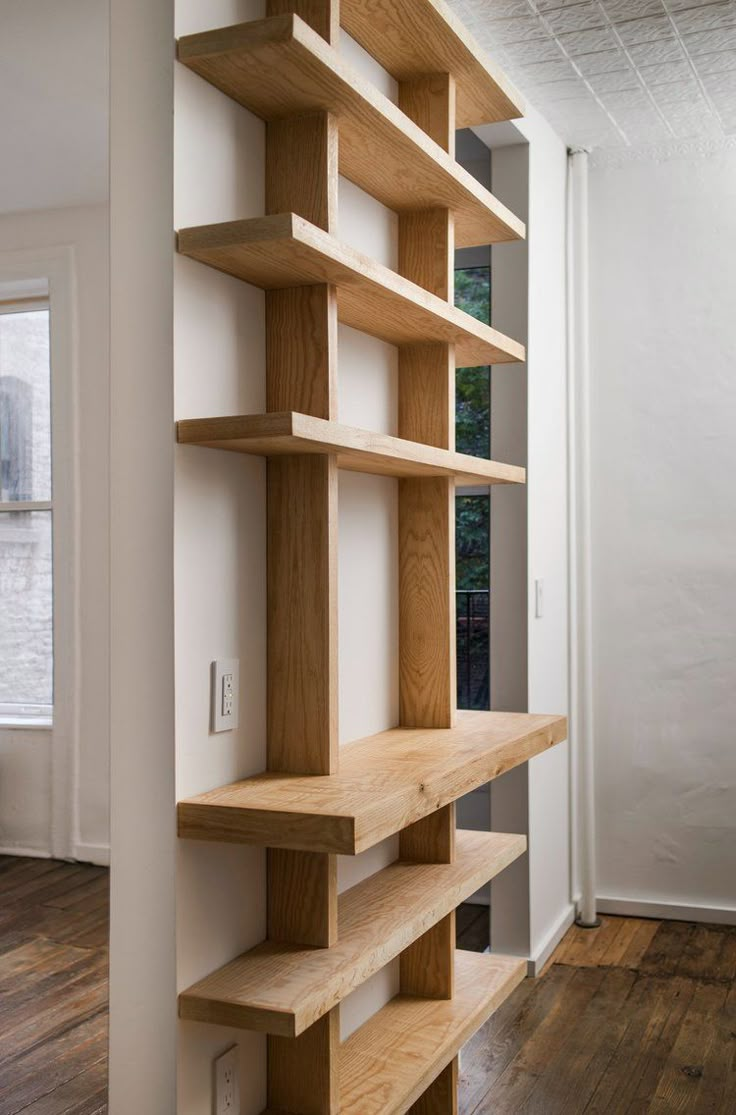 an empty room with wooden shelves on the wall and hard wood flooring in it