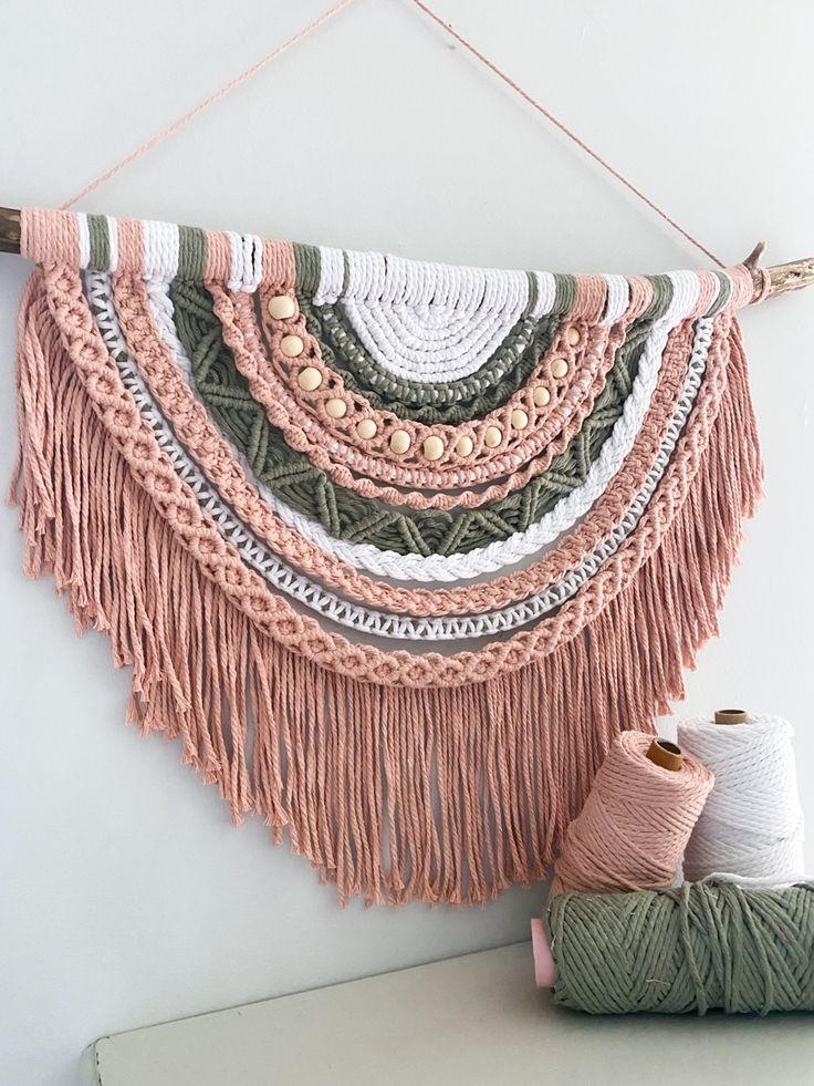 a wall hanging with yarn and two skeins of yarn on top of it