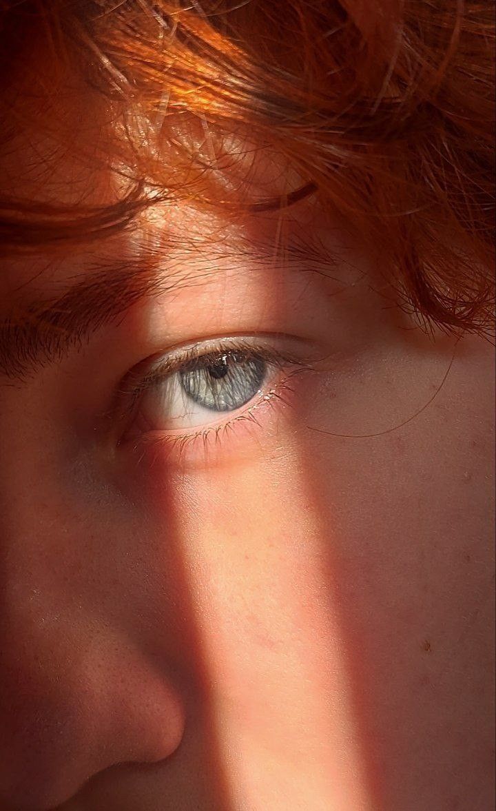 a close up of a person's face with the sun shining on their eyes