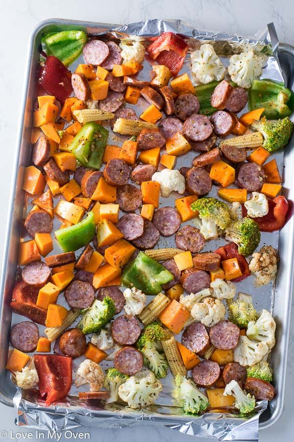 sausage, broccoli, cauliflower and peppers on a baking sheet with aluminum foil