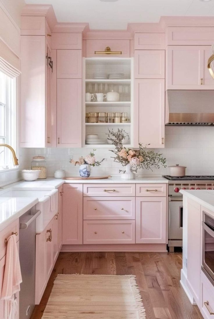 a kitchen with pink cabinets and white counter tops, wooden floors, and an oven