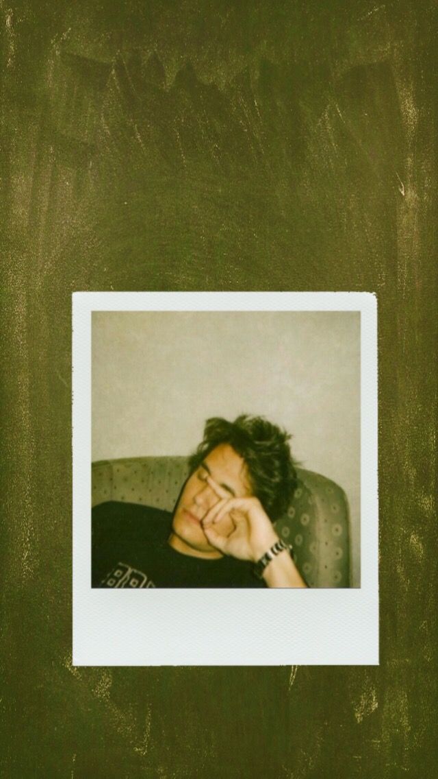 a polaroid photo of a man sitting on a couch with his hand to his face