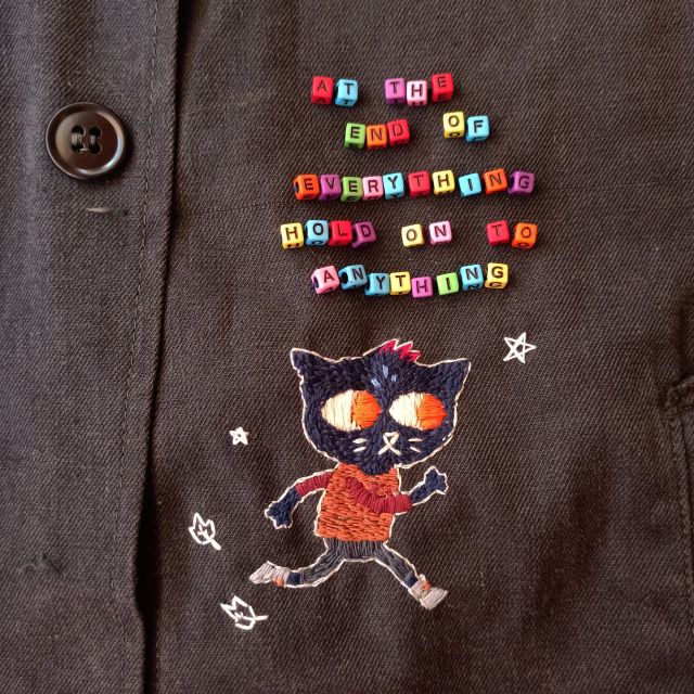 a close up of a person's shirt with buttons on it and an image of a cat