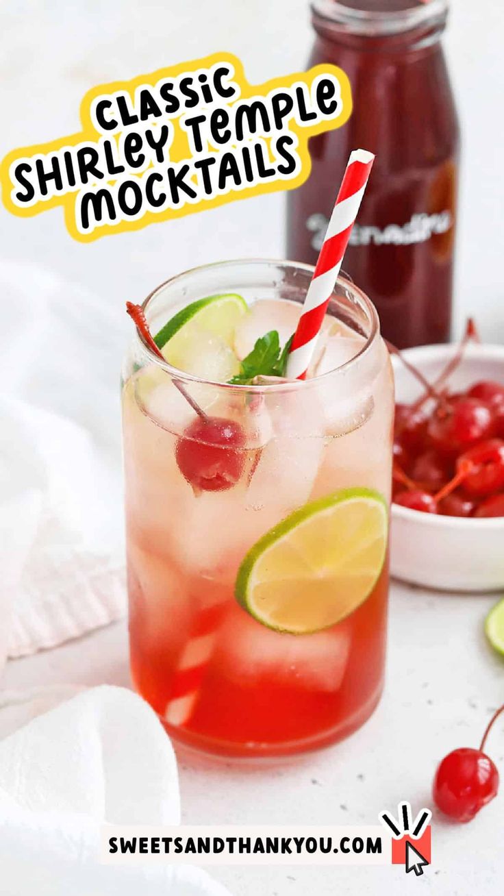 a glass filled with a drink next to a bowl of cherries and limes