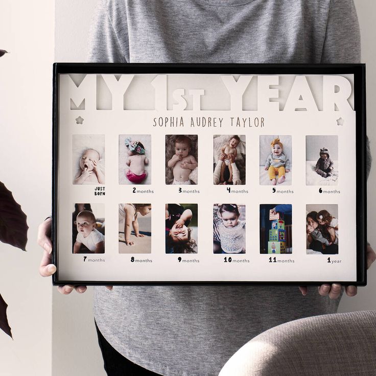 a person holding up a framed photo in front of a white wall with the words my 1st year on it