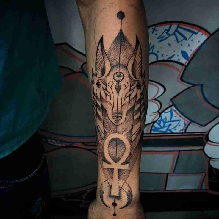 a man's arm with a wolf and an egyptian symbol on the side of it