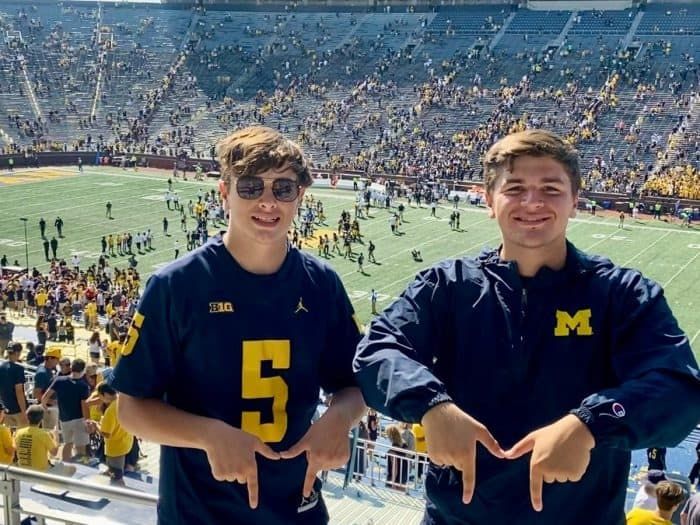 two young men standing next to each other at a football game