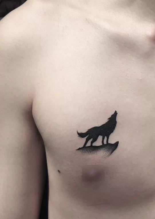 a man's chest with a tattoo of a wolf on the left side of his chest