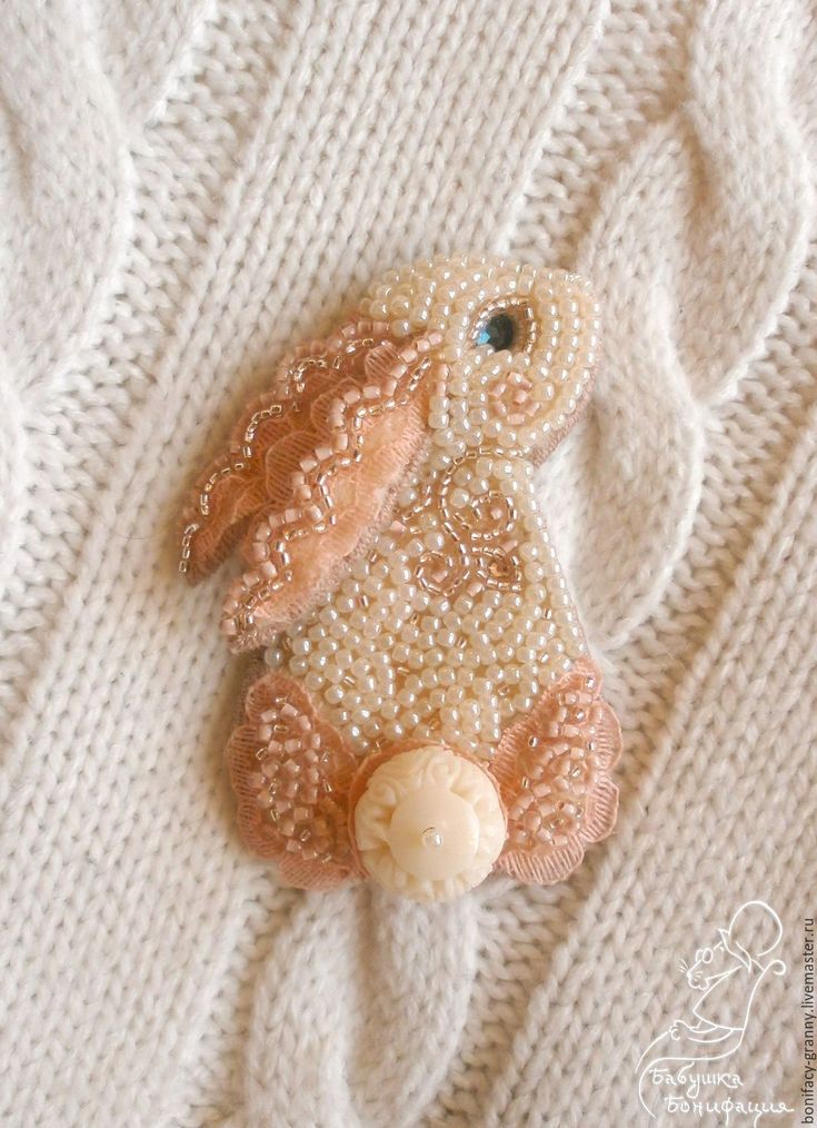 a close up of a stuffed animal on a white sweater with pearls and beads in the shape of a bunny