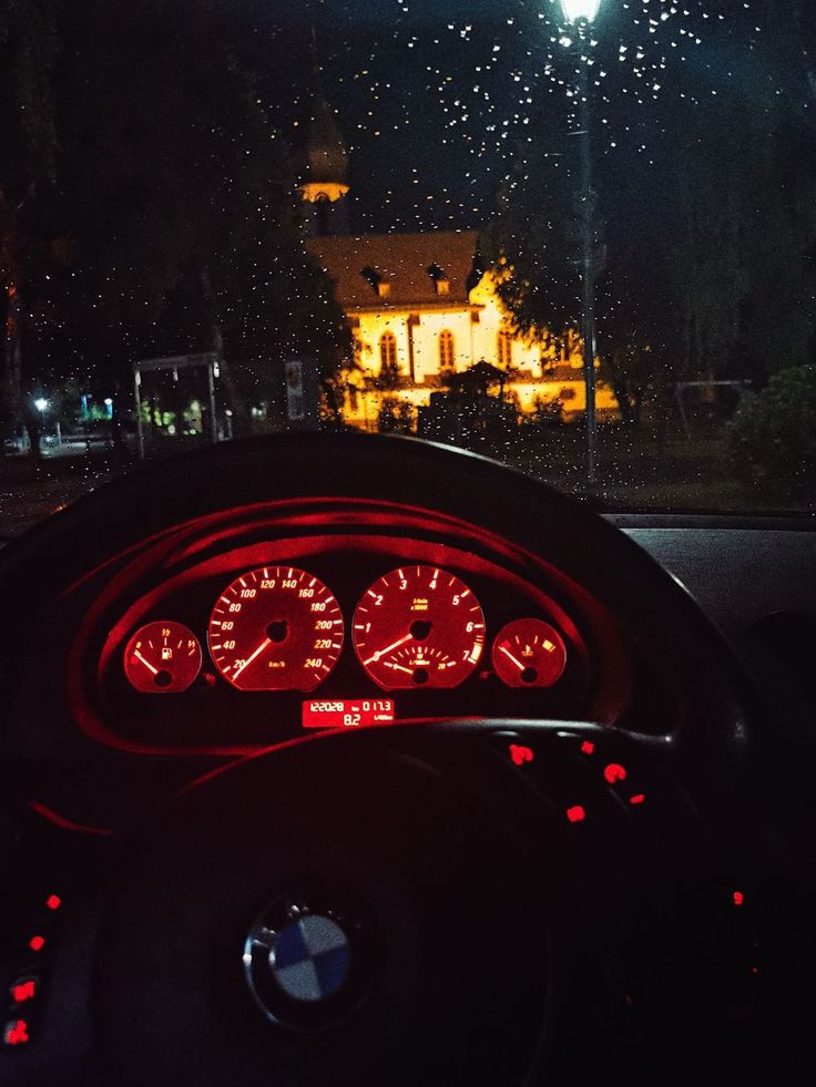 the dashboard of a car at night with fireworks in the sky and buildings behind it