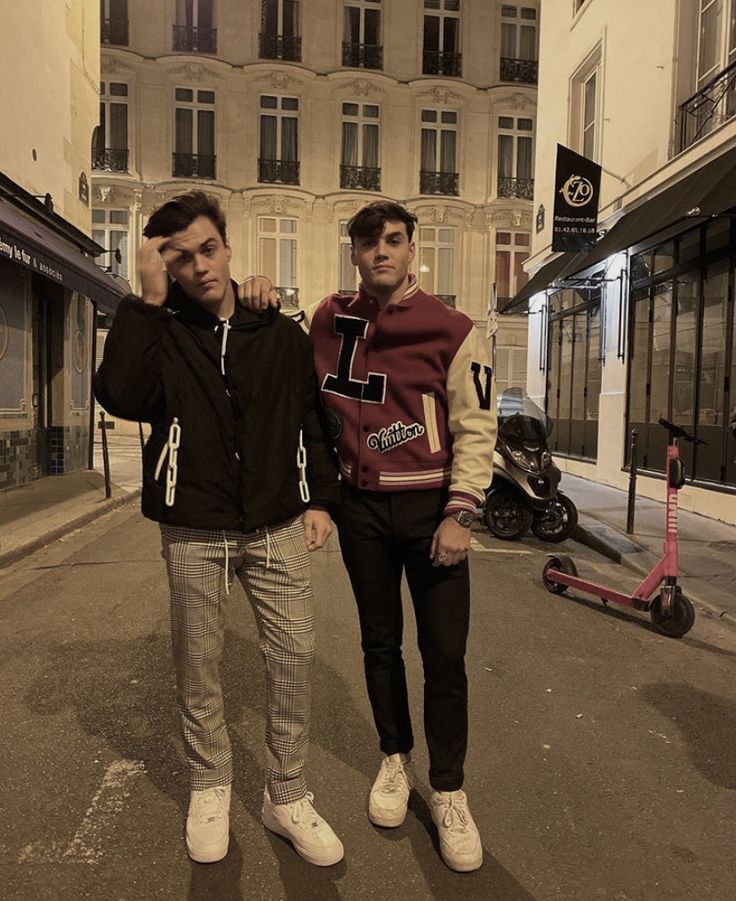 two young men standing next to each other on the street