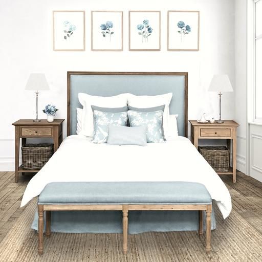 a bed with blue and white pillows on top of it next to two nightstands