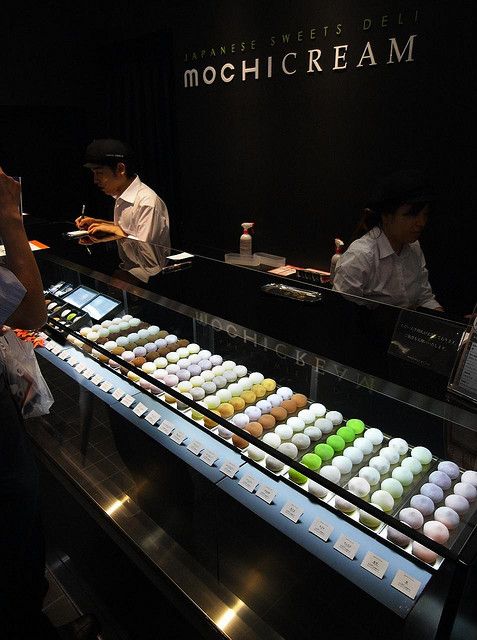 people standing in front of a display case filled with cupcakes