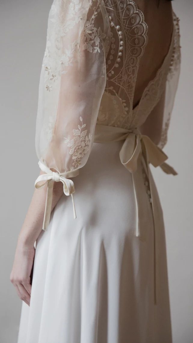 the back of a woman's wedding dress with sheer sleeves and lace on it