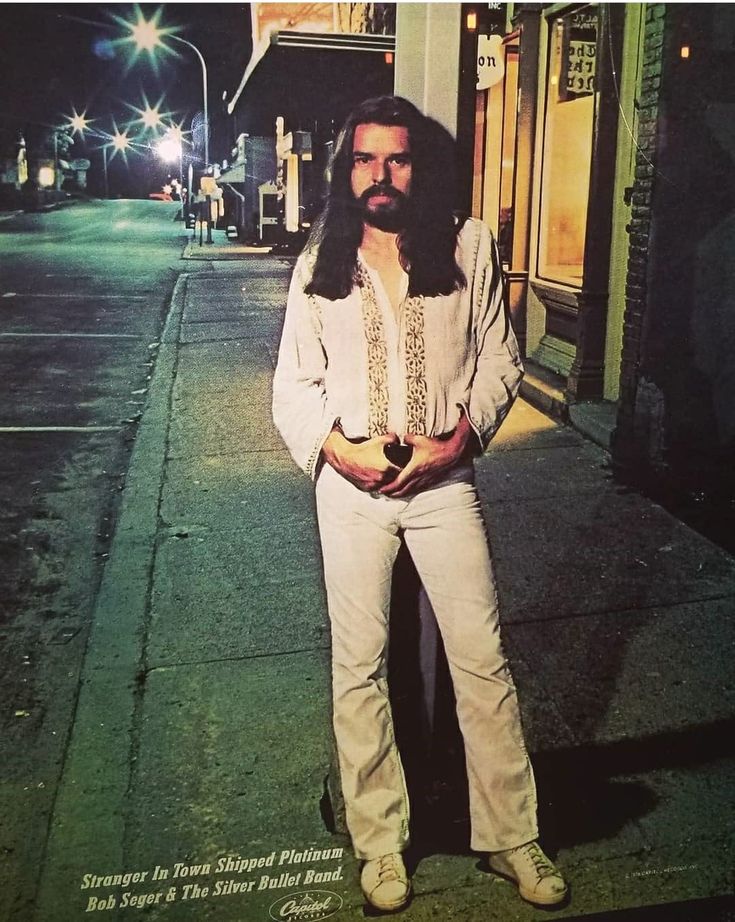 a man with long hair and beard standing on the sidewalk