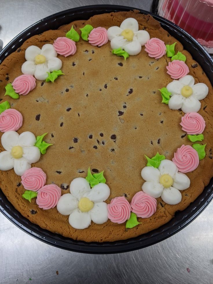 a chocolate cake with pink, white and green flowers in the shape of a circle