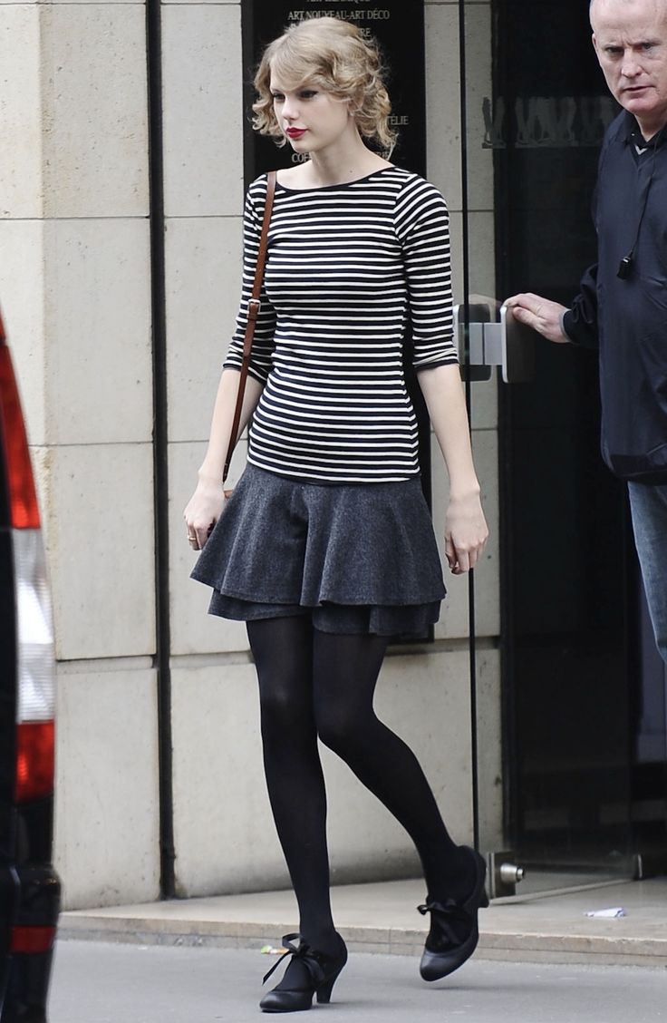 a woman in black and white dress walking down the street