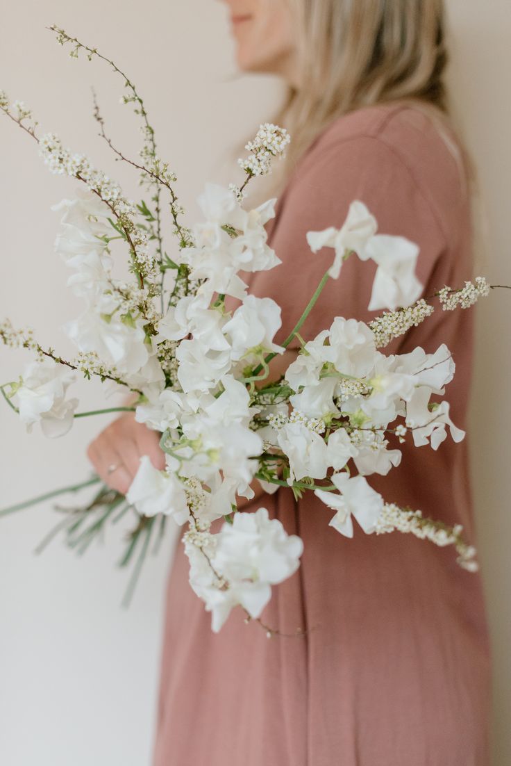 a woman holding a bouquet of white flowers