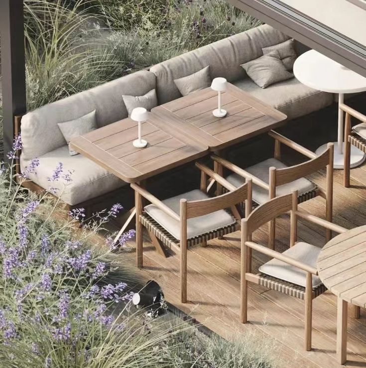 an outdoor seating area with wooden tables and chairs, surrounded by lavender flowers in the foreground