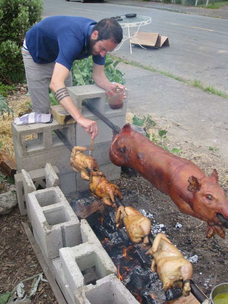 a man is grilling some meat on an outdoor bbq with two pig heads