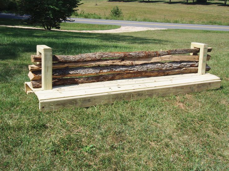 a bench made out of logs sitting in the grass