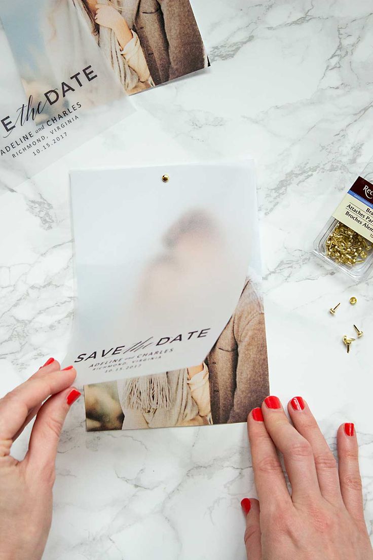 a person holding up a magazine on top of a marble table with gold studs