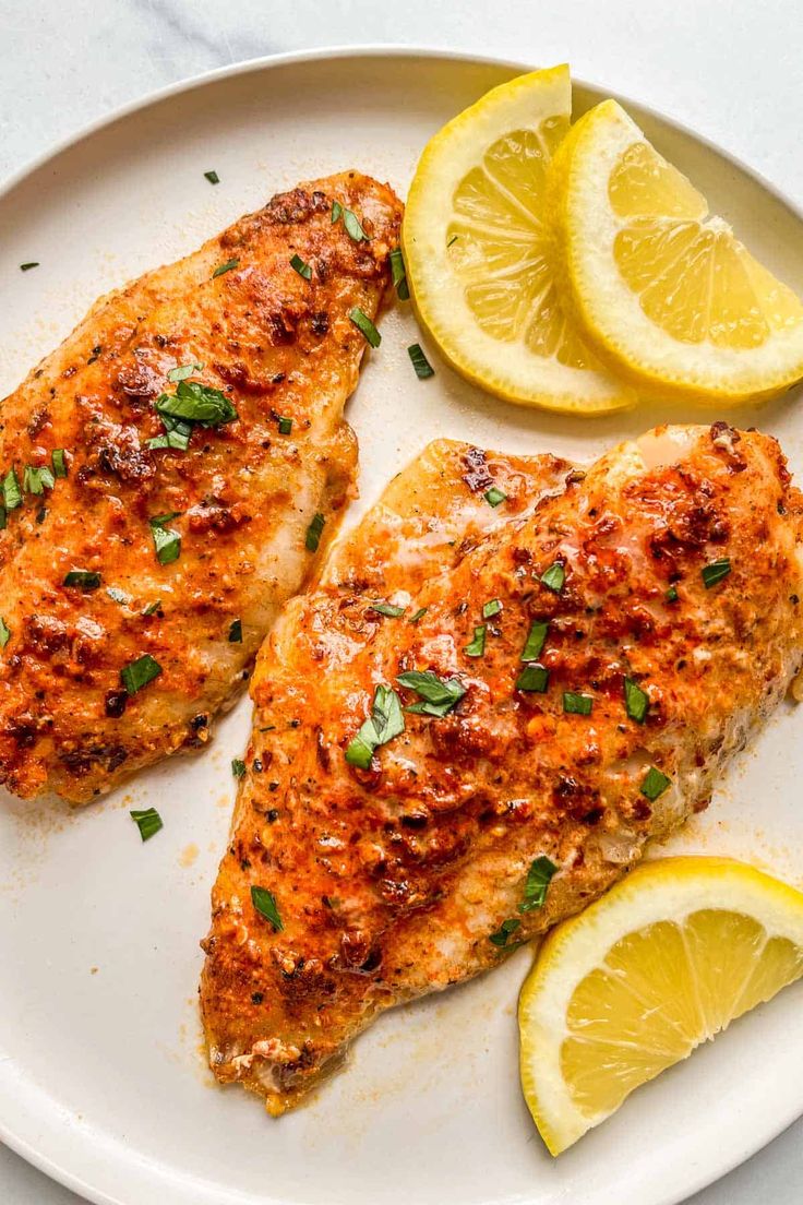 two pieces of chicken on a plate with lemons