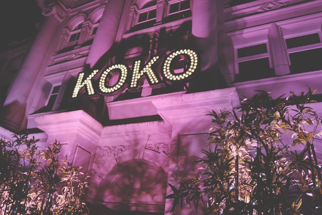 the koko sign is lit up at night in front of a building with trees