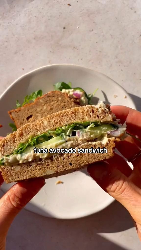 a sandwich with lettuce and other vegetables on it is being held up by someone's hand