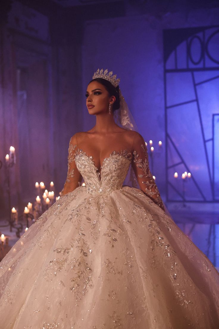 a woman in a wedding dress standing next to candles and wearing a tiara with her hands on her hips