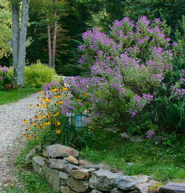 a gravel path with flowers and trees in the background