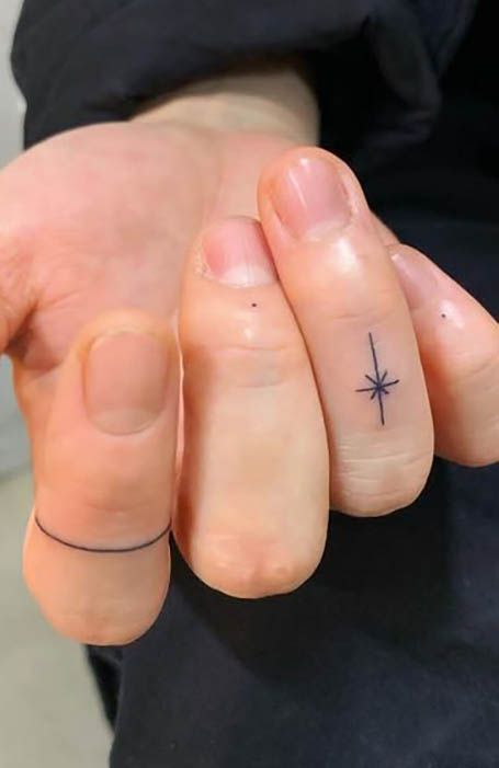 a person's hand with a tiny star tattoo on the middle finger and an arrow in the middle