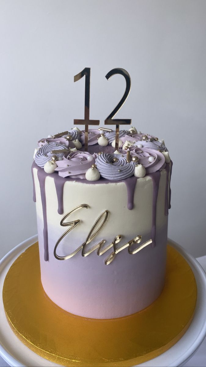 a purple and white cake with the number twelve on top is sitting on a gold plate