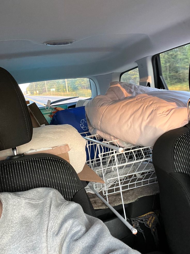 two people sleeping in the back seat of a car, with one person laying on a bed