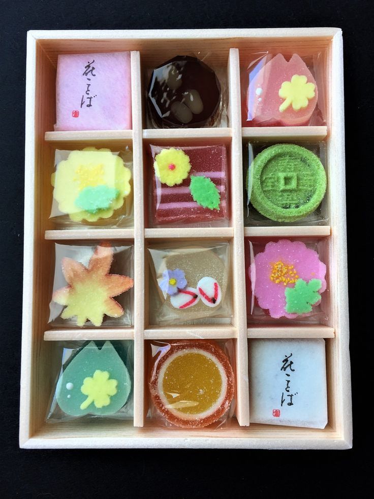 an assortment of different types of candies in a wooden tray on a black surface