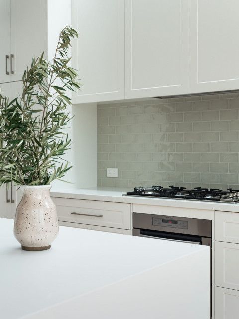 a white vase with a plant in it sitting on a counter top next to a stove