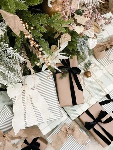 presents wrapped in brown paper and tied with black ribbon are sitting on the floor next to a christmas tree