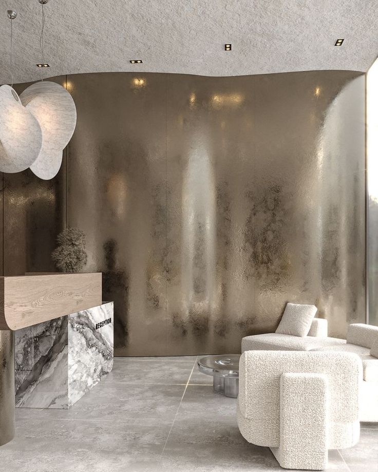 a living room filled with white furniture next to a large wall covered in metallic foil