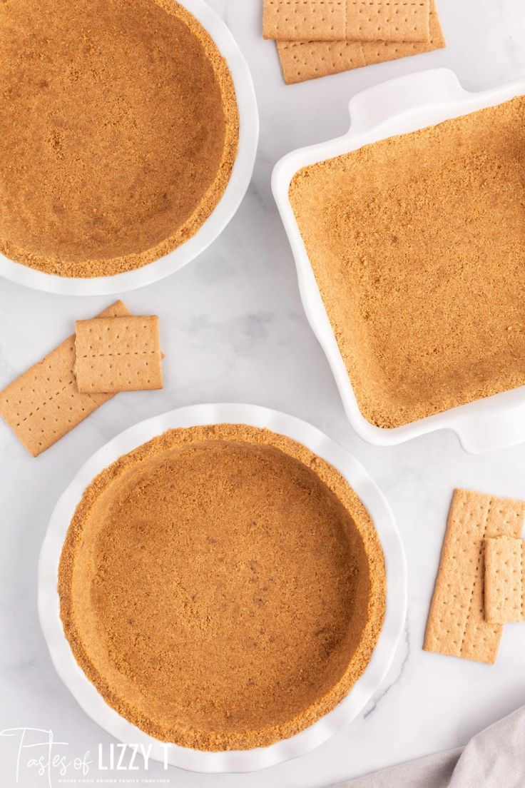 three white bowls filled with graham crackers on top of a marble counter next to two plates