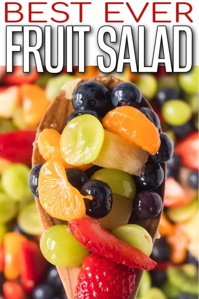 a wooden spoon filled with fruit salad on top of a table