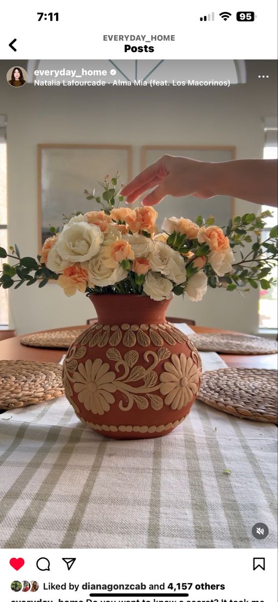 a vase filled with white and orange flowers on top of a tablecloth covered table