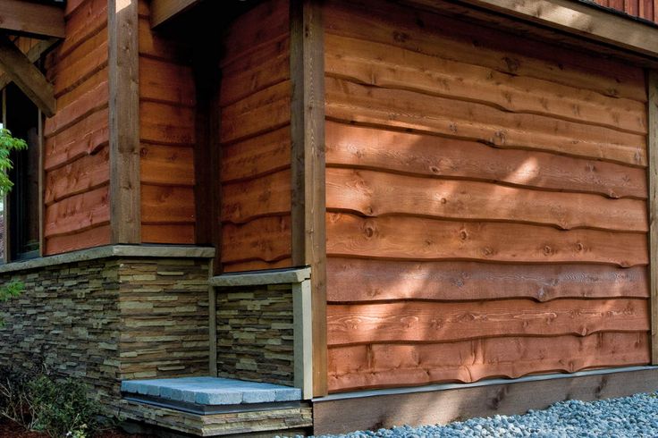 the side of a house with wood siding and stone steps leading up to it's front door